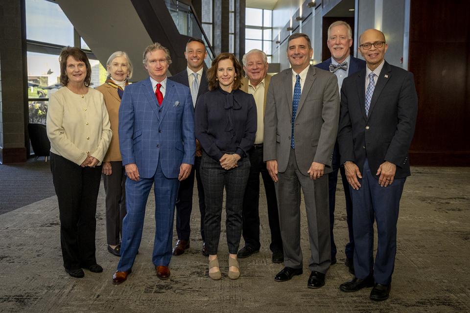 Member of the COTC Board of Trustees stand in a line shoulder to shoulder in the Reese Center.