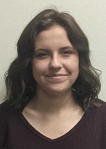 Headshot of Hannah with long dark hair, v-neck sweater