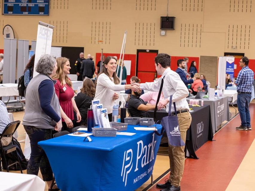 An employer shakes hands with a student at the career fair.