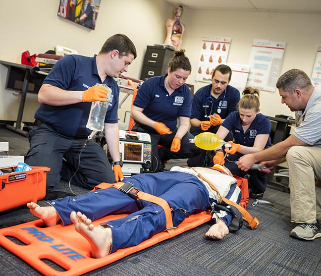 Four students working on a dummy patient with instructor overseeing them