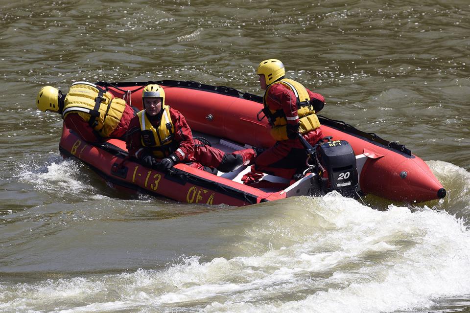 Firefighters  navigate rough waters in a rescue boat .