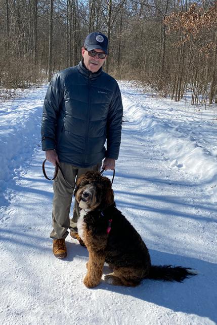 Gary Johnson standing next to his dog on a snowy trail. 