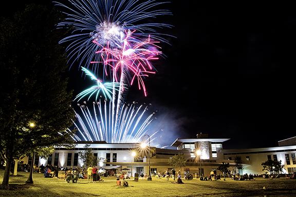 Fireworks erupt against a black sky above the Warner Center. 