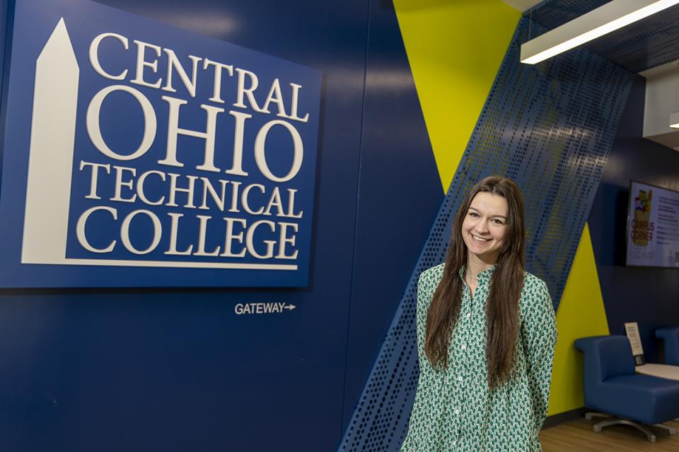 Portrait of Lexi McPeck standing next to a COTC logo on the wall of the Pataskala campus.