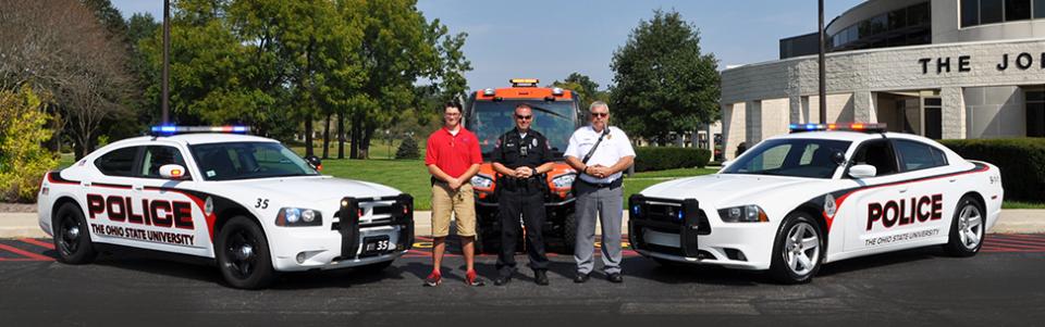three men standing in front of Ohio State University squad cars
