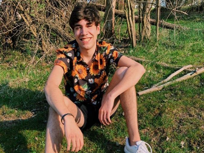 Samuel Wolf sits in the grass.