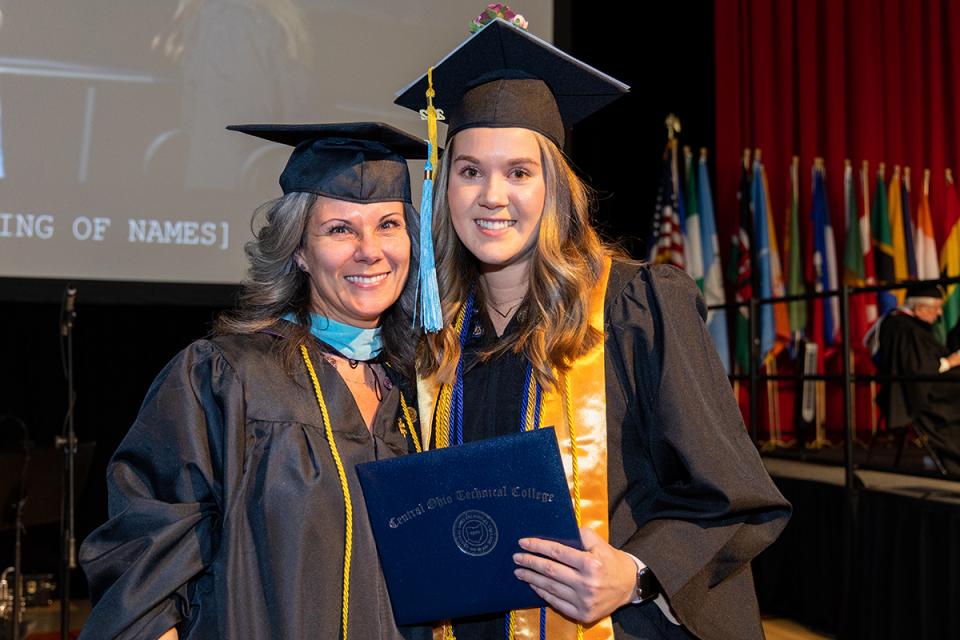 Lora Smith stands next to Lydia Smith who is holding her COTC diploma after just walking across the stage at COTC's commencement ceremony in December 2022.