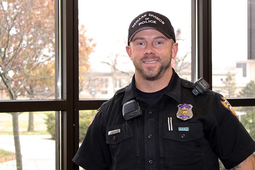 White man in police officer uniform smiling at camera, COTC alumnus Steven Carles