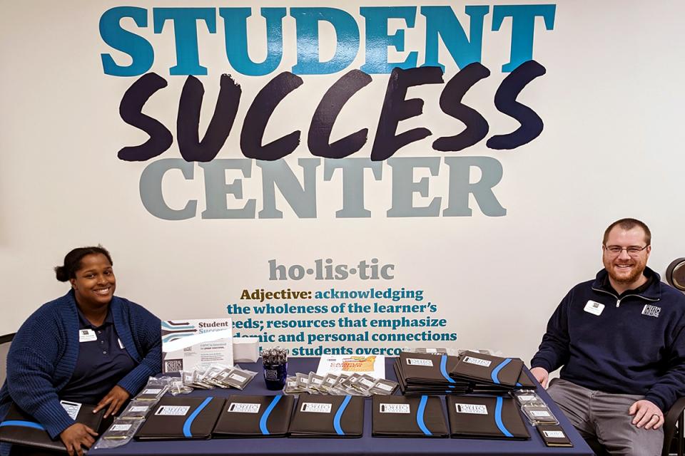 Student success coaches sit in front of a wall that says Student Success Center.