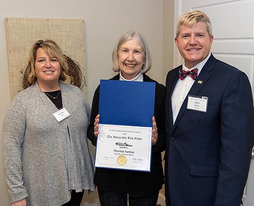 two women and one man on right wearing suit, middle woman holding certificate