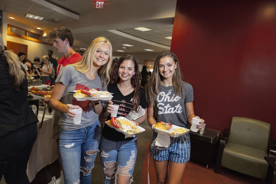 Three students hold trays of food from the campus cafeteria. 